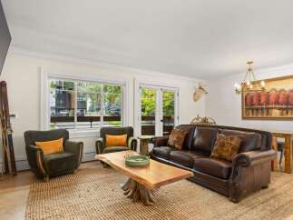 Experience rustic charm in this inviting living room, featuring a rich leather sofa and plush green armchairs perfect for cozy evenings.