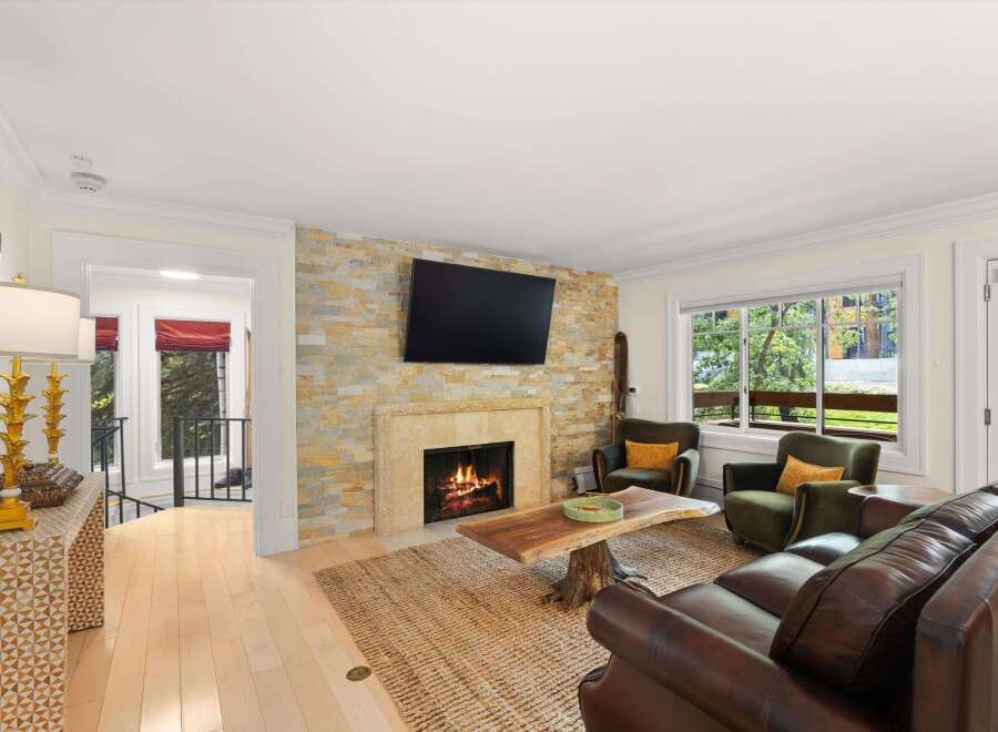 Cozy up by the natural stone fireplace in this inviting living room, featuring plush leather seating and two accent chairs perfect for conversation.