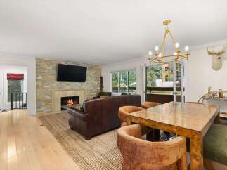 Experience elegant living in this beautifully appointed dining and living area, featuring a cozy fireplace with a stacked stone accent wall and a large flat-screen TV.