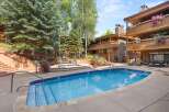 Enjoy a refreshing dip in the sparkling blue pool or relax in the adjacent hot tub, surrounded by lush greenery and mountain-style architecture.