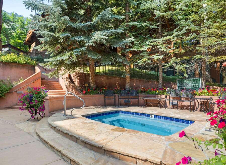 Enjoy a relaxing dip in this private hot tub, surrounded by lush greenery and vibrant flowers.