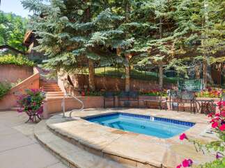 Enjoy a relaxing dip in this private hot tub, surrounded by lush greenery and vibrant flowers.