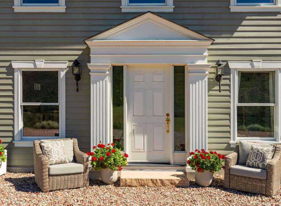 Charming home featuring a welcoming entrance with a classic white door, flanked by elegant fluted columns and decorative pediment.