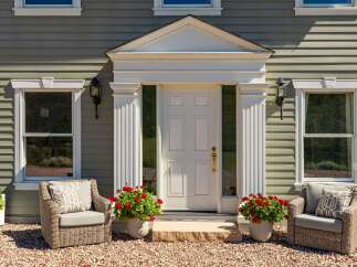 Charming home featuring a welcoming entrance with a classic white door, flanked by elegant fluted columns and decorative pediment.