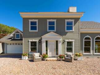 Charming home with a welcoming entrance, featuring a white double door and elegant columns.
