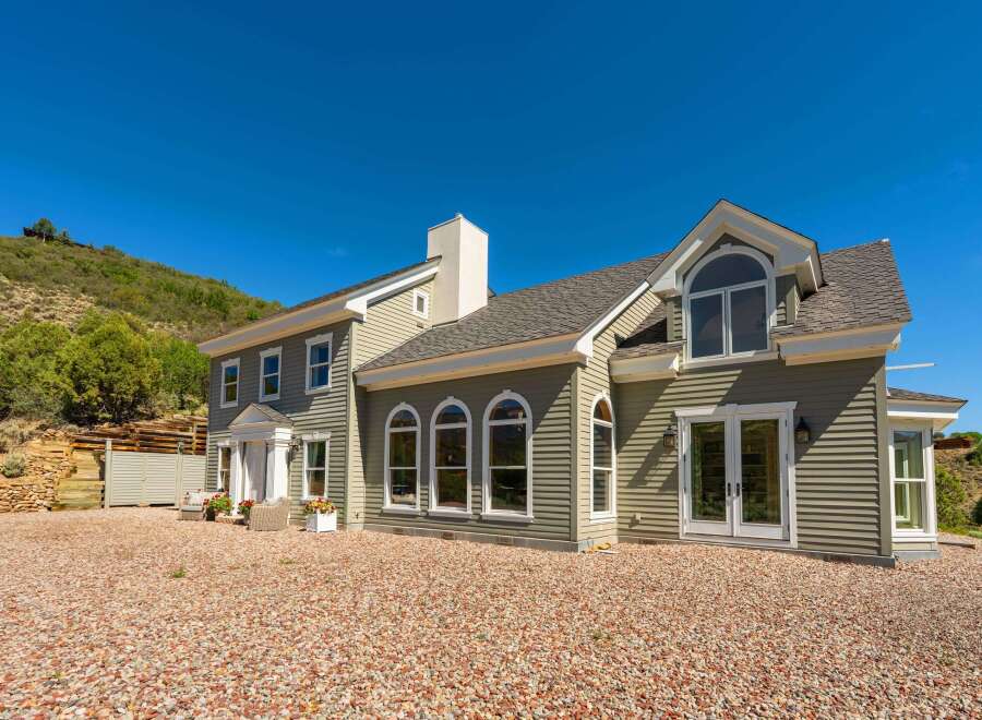 This stunning home boasts a charming exterior with light green siding and a welcoming white-trimmed entrance.