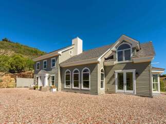 This stunning home boasts a charming exterior with light green siding and a welcoming white-trimmed entrance.