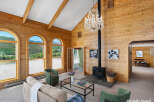 Experience breathtaking mountain views from this stunning living room, featuring a vaulted wood-paneled ceiling and a grand crystal chandelier.
