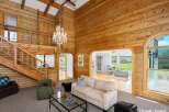 Experience rustic charm in this stunning living room, featuring soaring wood-paneled walls and a grand chandelier.