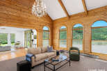 Experience breathtaking mountain views from this stunning living room, featuring a vaulted wood-paneled ceiling and a grand crystal chandelier.