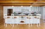 This charming kitchen features white cabinetry, a stainless steel refrigerator, and a spacious island with bar stools, perfect for casual dining.