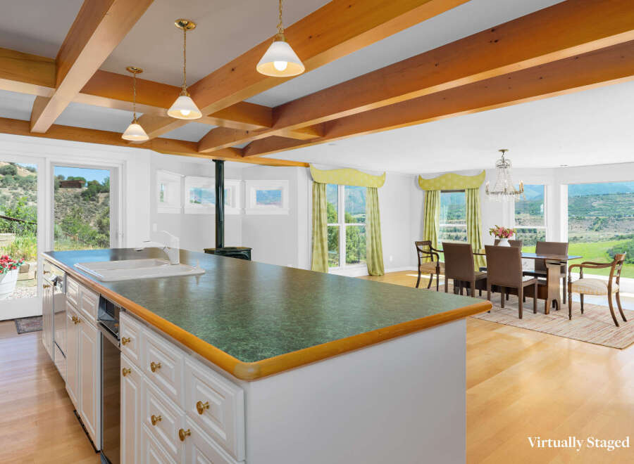 Experience breathtaking mountain views from this spacious kitchen and dining area, featuring a large island with a sink and ample cabinet space.