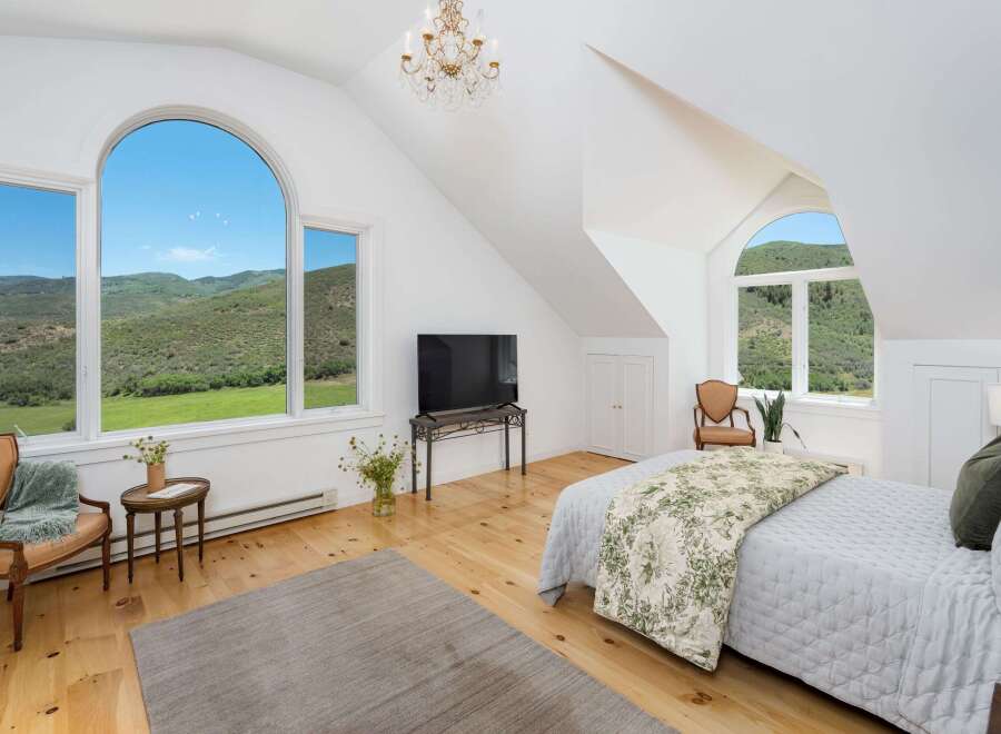 Experience breathtaking mountain views from this stunning bedroom, featuring a grand arched window that floods the space with natural light.