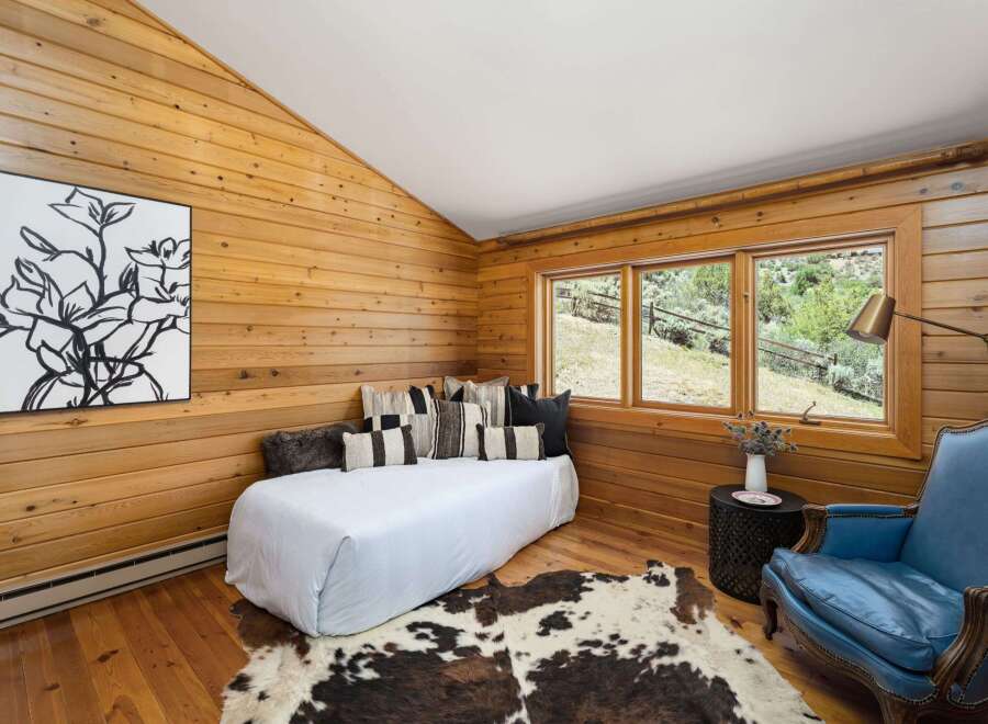 Experience rustic charm in this cozy bedroom featuring warm wood-paneled walls and a vaulted ceiling.