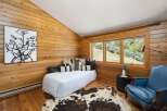 Experience rustic charm in this cozy bedroom featuring warm wood-paneled walls and a vaulted ceiling.