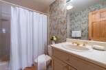 This charming bathroom features a classic floral wallpaper and a white tiled shower with a textured shower curtain.