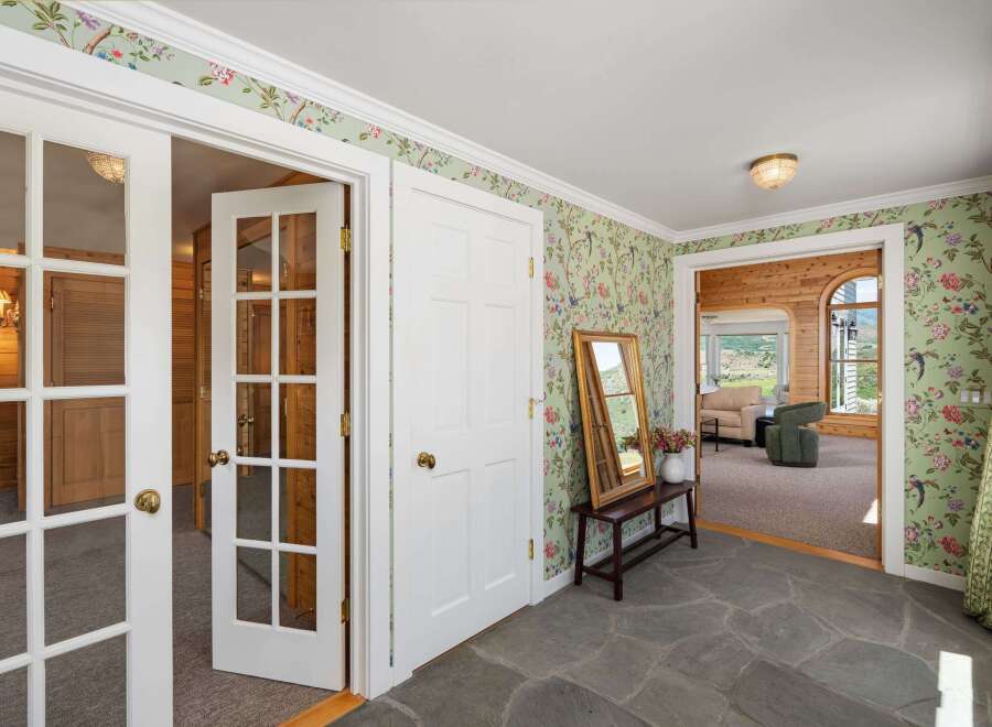Step into this charming entryway featuring a unique floral wallpaper and a stone floor.