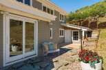 Enjoy outdoor living with this charming patio featuring a white metal bench with decorative pillows and a stone pathway leading to a lush garden.