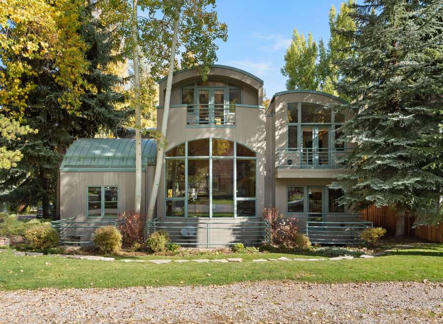 This stunning modern home features a unique architectural design with curved roofs and expansive windows that flood the interior with natural light.