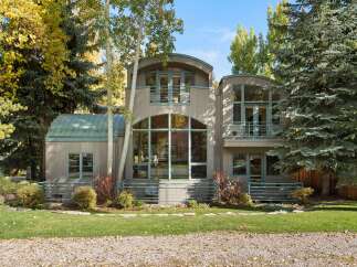 This stunning modern home features a unique architectural design with curved roofs and expansive windows that flood the interior with natural light.