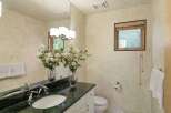 This elegant bathroom features a spacious vanity with a dark green marble countertop and a white undermount sink, complemented by modern chrome fixtures.