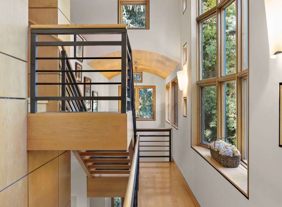 Experience modern luxury in this stunning home featuring a striking multi-level staircase with sleek black railings and warm wood accents.