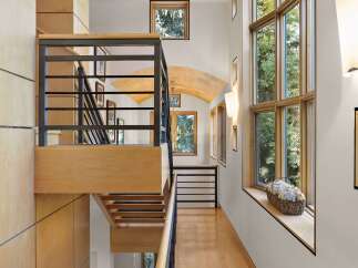 Experience modern luxury in this stunning home featuring a striking multi-level staircase with sleek black railings and warm wood accents.