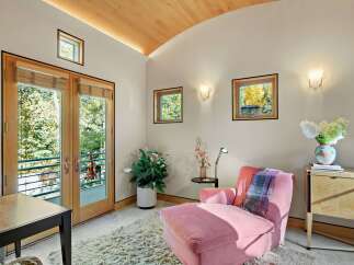 This inviting room features a plush pink chaise lounge, perfect for relaxation, complemented by a soft, textured rug.