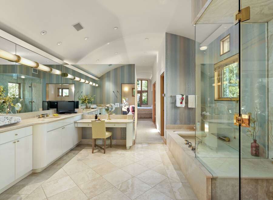 Indulge in luxury in this expansive master bathroom featuring a spacious vanity area with ample counter space and a built-in dressing table.