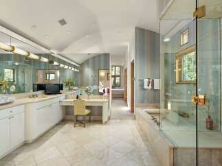 Indulge in luxury in this expansive master bathroom featuring a spacious vanity area with ample counter space and a built-in dressing table.