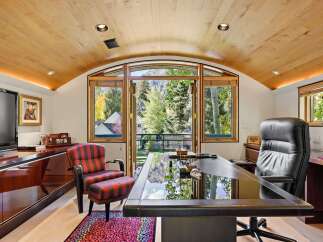 Experience luxury and productivity in this executive office, featuring a sleek glass-top desk and a comfortable leather executive chair.