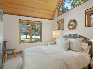 Experience serene living in this charming bedroom, featuring a vaulted wood-paneled ceiling and large windows that flood the space with natural light.