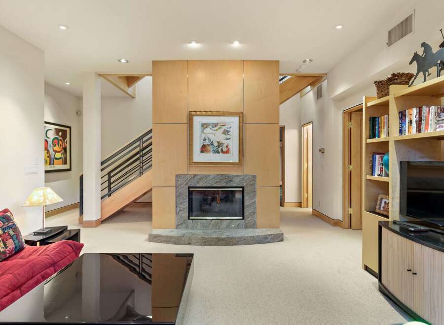 This spacious living area features a modern fireplace as the focal point, surrounded by warm wood paneling and a granite hearth.