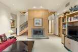 This spacious living area features a modern fireplace as the focal point, surrounded by warm wood paneling and a granite hearth.