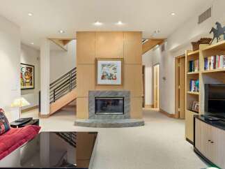 This spacious living area features a modern fireplace as the focal point, surrounded by warm wood paneling and a granite hearth.