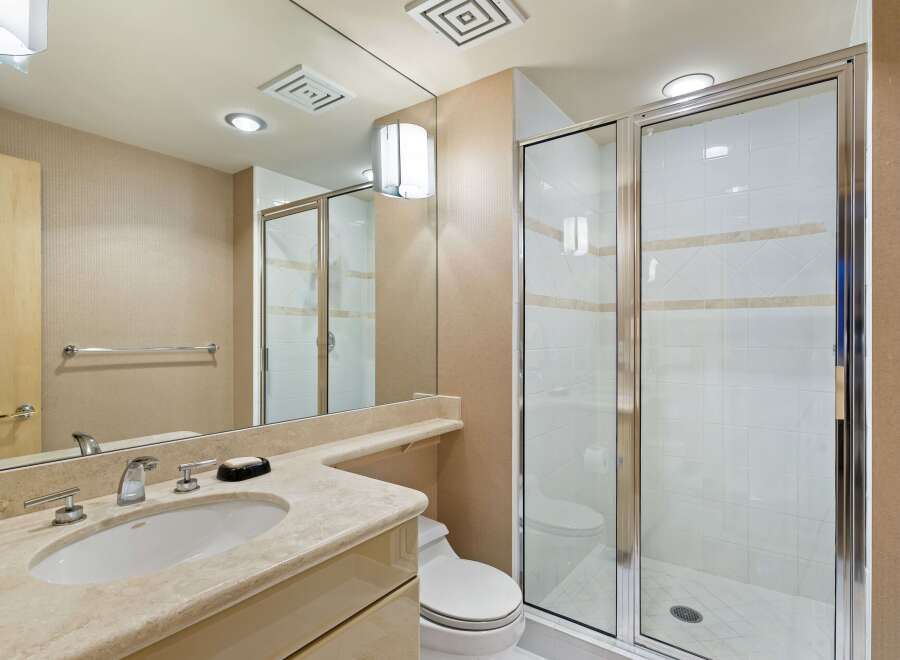 This elegant bathroom features a spacious vanity with a marble countertop and a modern faucet, complemented by a large mirror.