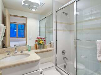 This bright and airy bathroom features a spacious vanity with a stone countertop and a modern sink, complemented by a large mirror reflecting the elegant tiling.