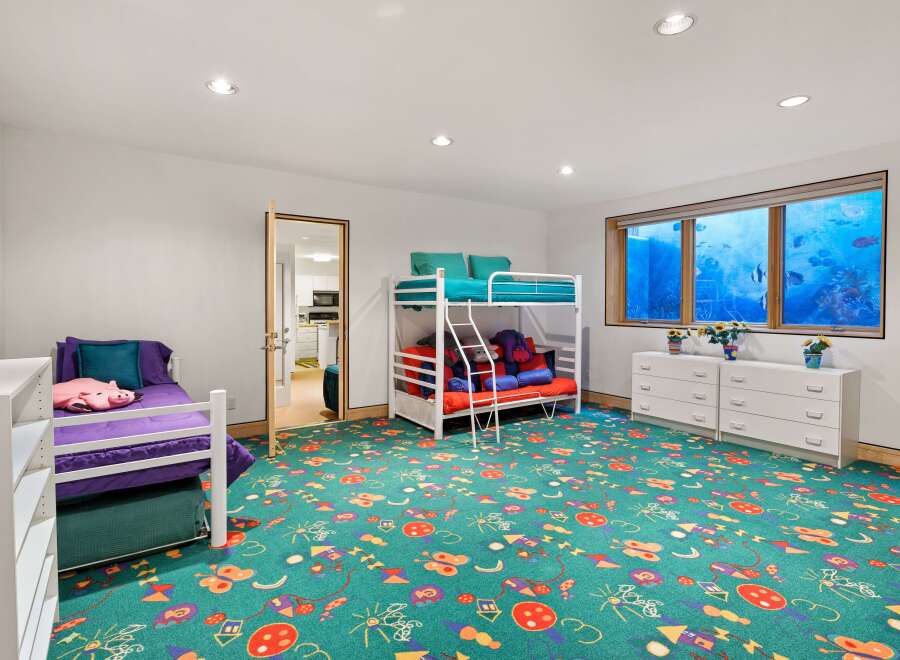 This playful children's bedroom features a vibrant green carpet adorned with colorful kites and butterflies, creating a whimsical atmosphere.