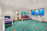 This playful children's bedroom features a vibrant green carpet adorned with colorful kites and butterflies, creating a whimsical atmosphere.