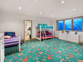 This playful children's bedroom features a vibrant green carpet adorned with colorful kites and butterflies, creating a whimsical atmosphere.