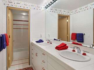 This charming bathroom features a double vanity with white tile countertops and a playful star and moon wallpaper.