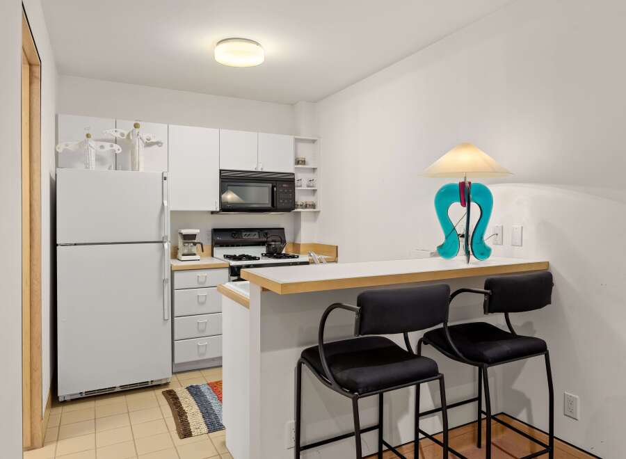 Discover this charming kitchen featuring a full-sized refrigerator, a microwave, and a gas range perfect for home-cooked meals.