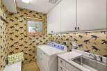 This charming laundry room features a playful dog-themed wallpaper that adds a unique personality to the space.