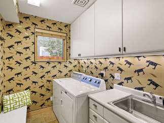 This charming laundry room features a playful dog-themed wallpaper that adds a unique personality to the space.