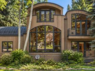 Experience modern luxury in this stunning wood-clad home, featuring a unique curved roofline and expansive arched windows that flood the interior with natural light.