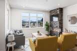 Experience modern living with this stunning living room featuring a sleek stone fireplace and a large window offering breathtaking mountain views.