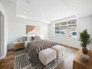 Experience modern comfort in this beautifully appointed bedroom, featuring a plush king-sized bed with elegant taupe bedding and a striking abstract art piece above.