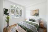Experience modern comfort in this beautifully staged bedroom, featuring a large window with scenic forest views.