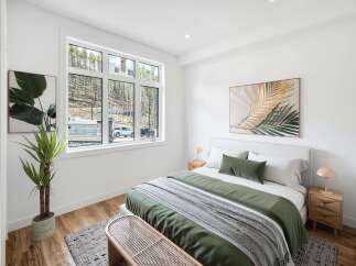 Experience modern comfort in this beautifully staged bedroom, featuring a large window with scenic forest views.
