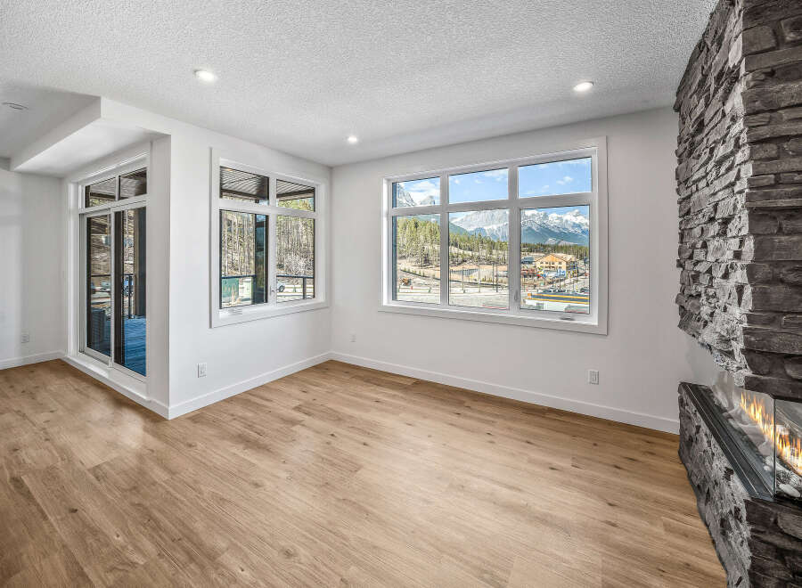 Experience breathtaking mountain views from this stunning living room, featuring a modern gas fireplace with a striking stone surround.
